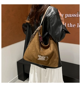 Detail of a brown suede hobo bag featuring white embroidery and striped drawstring