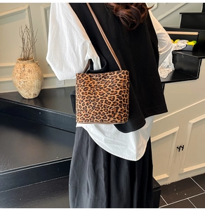 Close-up of leopard print suede shoulder bag with brown leather strap on model