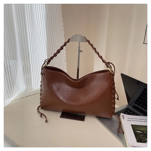 Détail du sac à bandoulière marron rétro avec sangle tressée et détails de cordon latéral