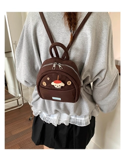 Detail of mini vintage brown suede backpack featuring wooden buttons and dog embroidery patch