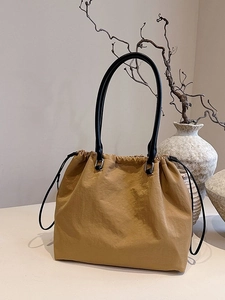 Minimalist tan drawstring tote bag with black handles in a high-capacity casual style