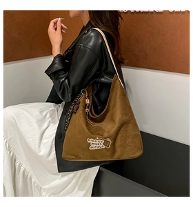 Detailed embroidery on brown suede hobo bag with tassel and wide white strap