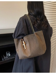 Grand sac cabas rétro en daim marron foncé avec pendentif perlé porté par un mannequin