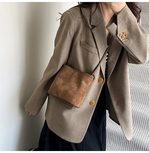 Close-up of brown suede crossbody bag styled with a matching brown oversized blazer coat