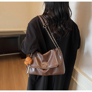Detail of vintage brown tote bag with metal chain strap and cute teddy plush charm