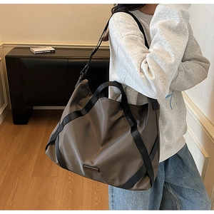 Detail der taupefarbenen Reisetasche mit großen Kapazität und schwarzen Gurtbändern