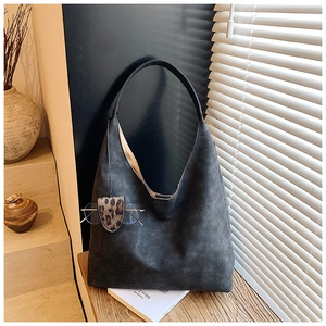 Detail of a black large capacity tote bag with matte leather texture and leopard tag