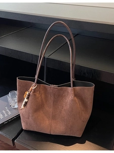 Sac cabas en daim marron avec pendentif en perles sur étagère en bois, style minimaliste