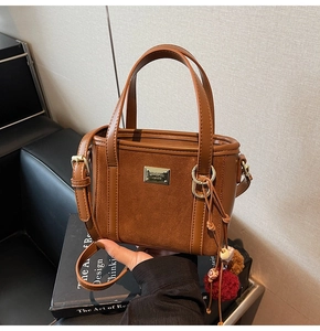 Detail of vintage brown bucket bag with tassel charms and metallic logo plate