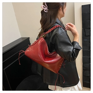 Détail du sac hobo bordeaux avec bandoulière tressée et texture en cuir brillant chic