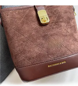 Macro shot of dark brown quilted bucket bag with matte suede panels and gold metal clasp