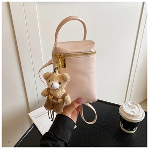 Détail du mini sac en cuir verni rose avec zips dorés et pendentif ours en peluche