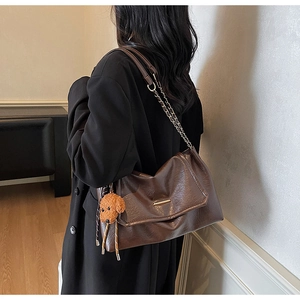 Detail of dark brown leather tote with chain strap and cute teddy bear plush charm