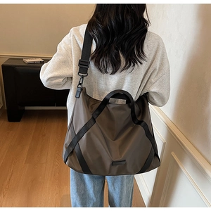 Braune Nylon-Reisetasche an Model mit großem Fassungsvermögen und schwarzen Riemen