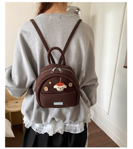 Detail of dark brown mini canvas backpack with cartoon dog patch and wooden buttons