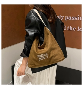 Brown suede tote bag with cartoon print and large capacity shown on model's shoulder