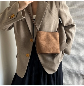 Détail d'un mini sac seau en daim marron avec fine bandoulière et style rétro