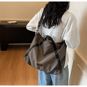 Detailansicht der großen kaffeebraunen Reisetasche, getragen über der Schulter