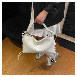 Détail d'un sac hobo en cuir blanc avec large poignée tressée et laçage latéral décoratif