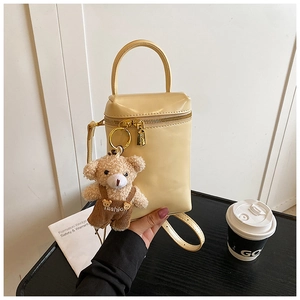 Détail du mini sac à main crème avec breloque ours en peluche et finitions dorées