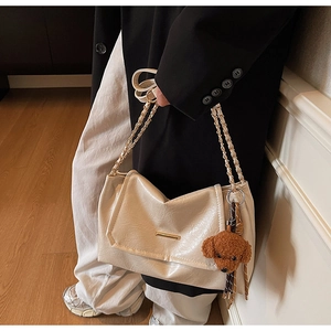 Detail of cream chain shoulder bag with golden hardware and cute brown teddy charm