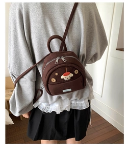 Close-up of brown suede mini backpack featuring cute cartoon puppy and wooden button
