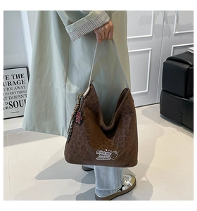 Detail of leopard print tote bag with cute bear pendant and wide beige shoulder strap