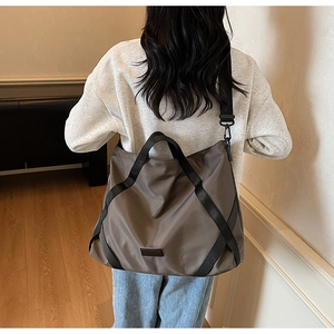 Braune Nylon Reisetasche mit schwarzen Riemen von Model im Raum getragen