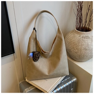 Detail of khaki tote bag with leopard charm on suitcase and aesthetic props