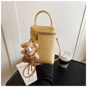 Détail du mini sac à main jaune crème avec un charm ours mignon en mode lifestyle