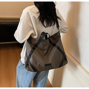 Rückansicht eines Modells mit einer großen dunkelbraunen Reisetasche in Wohnumgebung
