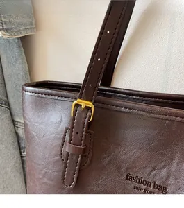 Close-up of brown pebbled leather tote with gold hardware and New York embossed text