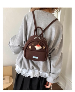 Close-up of brown suede mini backpack with wooden button and cute puppy patch detail
