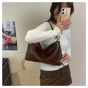 Détail du sac porté épaule vintage marron foncé avec laçage latéral et texture en cuir