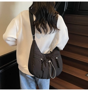 Rear view of black pleated crescent crossbody bag with white drawstring fasteners