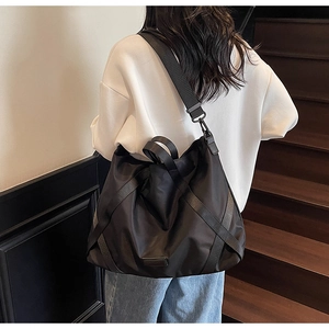 Rückansicht eines Modells mit einer großen schwarzen Reisetasche aus Nylon auf einer Treppe