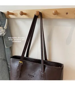 Detail of adjustable strap with gold metal buckle on a dark brown vintage tote bag