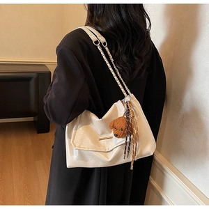 Detail of cream leather shoulder bag with gold chain strap and cute puppy charm