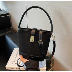 Close-up of black quilted suede bucket bag with leather base and gold metal buckle