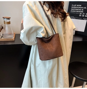 Detail view of the deep brown suede bucket bag with its minimalist thin shoulder strap