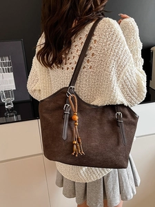 Retro dark brown frosted tote bag with ethnic wooden bead tassels worn by a model