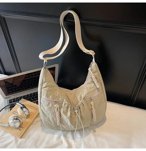Detail of green pleated nylon crescent bag with adjustable strap and front zip pockets