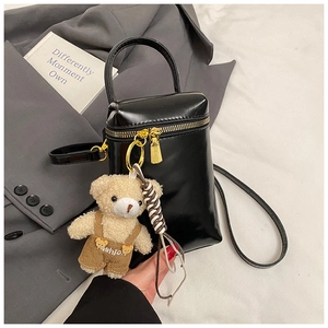 Détail du mini sac cylindrique noir en cuir brillant avec un pendentif ours mignon