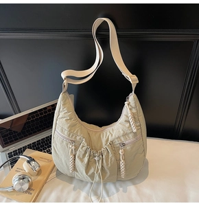 Detail of sage green pleated crescent bag with dual zippers and adjustable strap