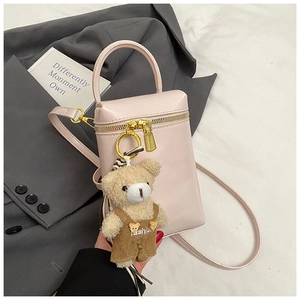 Détail du mini sac rose avec zip doré et breloque ours sur un arrière-plan élégant