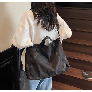 Moderne schwarze Nylon-Reisetasche mit verstärkten Riemen, von Model getragen