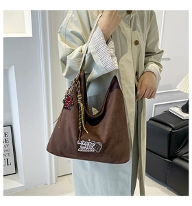 Detail of a brown suede hobo tote with a star embroidery patch and cute bear charm pendant