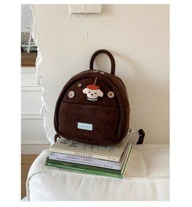 Detail of dark brown suede mini backpack featuring wooden buttons and cute plush dog charm