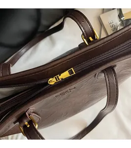 Close-up of the smooth metal zipper closure and gold hardware on the brown tote bag