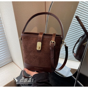 Detail of dark brown quilted bucket bag featuring a gold twist lock and adjustable strap